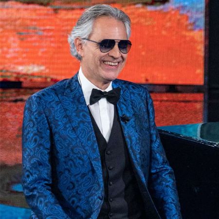 Andrea Bocelli in a blue tux poses for a picture.
